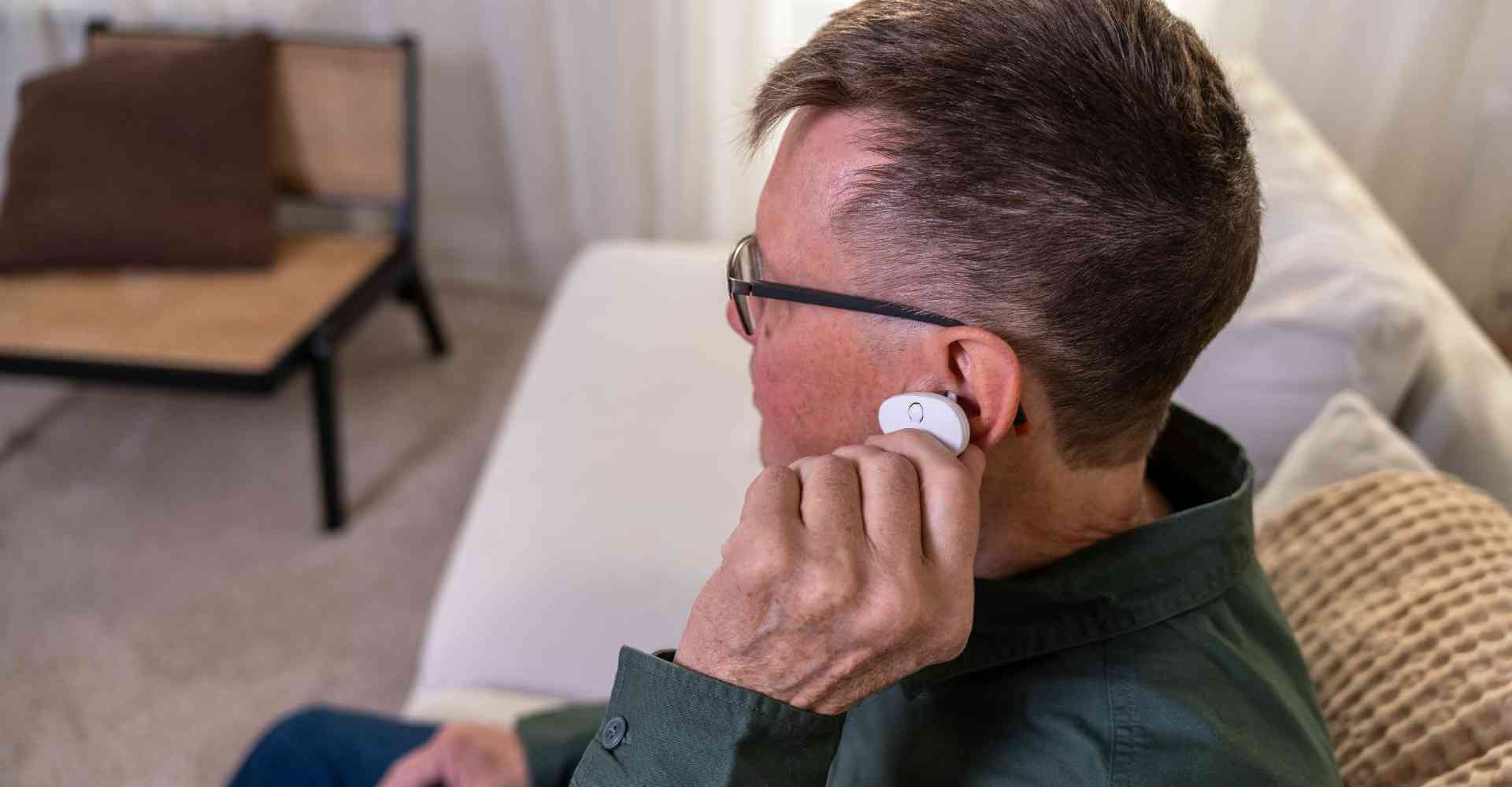User holding the EVANES device near their ear, demonstrating the simple, non-invasive application of the tVNS device.